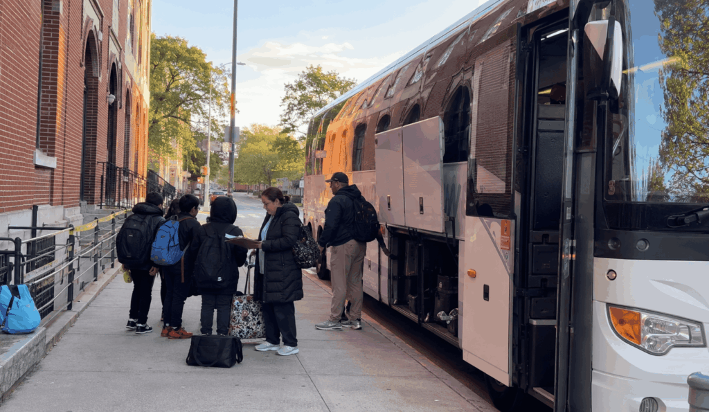 students and chaperones boarding a charter bus at a bronx school before a field trip to the intrepid museum
