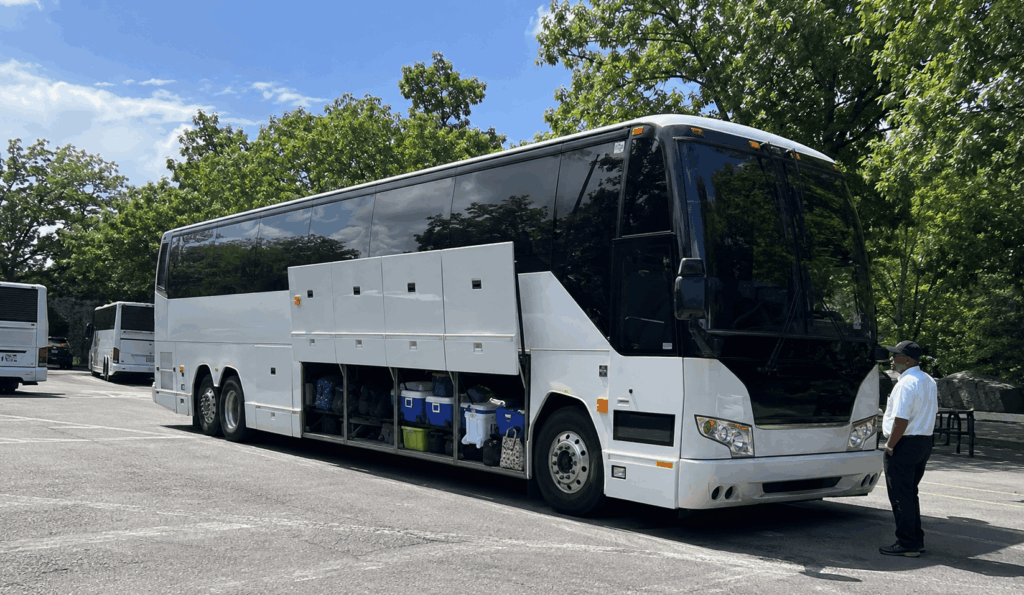 charter bus parked near the bronx zoo with open luggage bay storing lunch coolers and backpacks for a school field trip