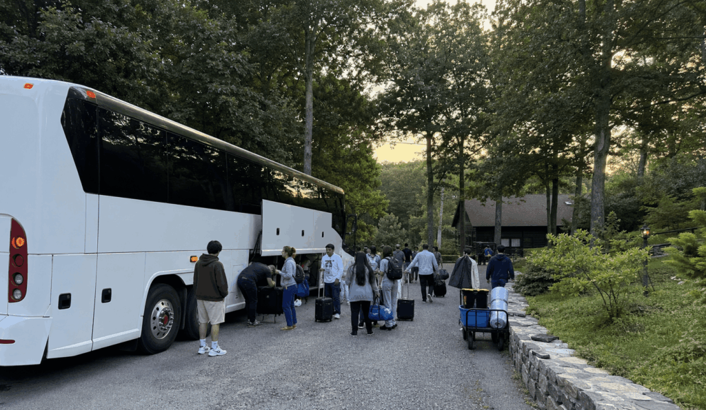 charter bus arriving with a church retreat group at a wooded hudson valley retreat center entrance