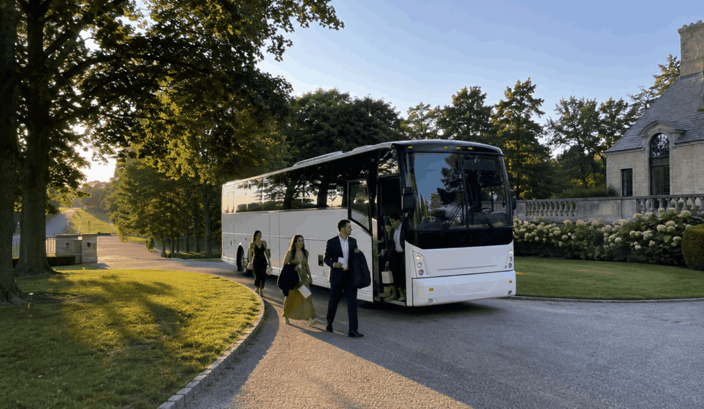 charter bus arriving at a long island estate wedding venue with guests near a grand driveway entrance