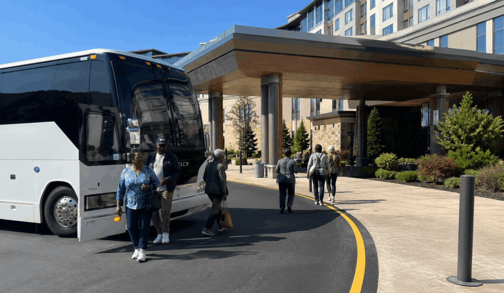charter bus dropping off a group at the main entrance area of resorts world catskills in monticello, new york